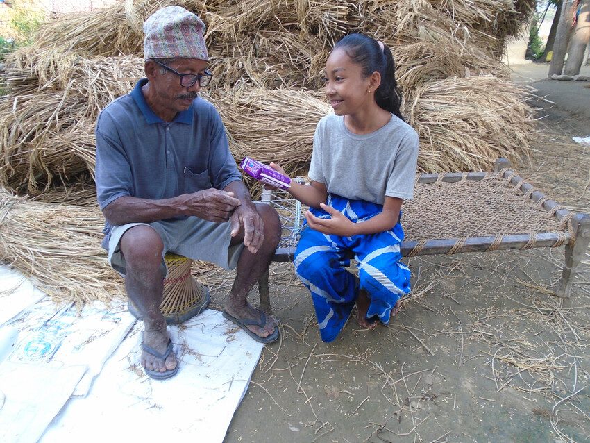 Tilakram, 64, gives his granddaughter a packet of sanitary pads.